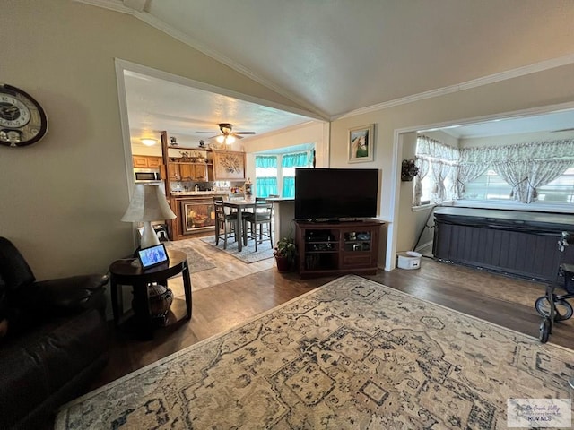 living room with hardwood / wood-style flooring, ceiling fan, crown molding, and vaulted ceiling