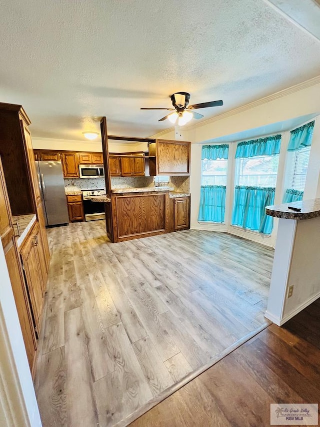 kitchen featuring stainless steel appliances, brown cabinetry, light wood-style flooring, and decorative backsplash