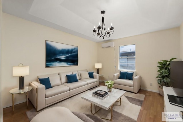 living room featuring a chandelier, a raised ceiling, light hardwood / wood-style flooring, and a wall unit AC