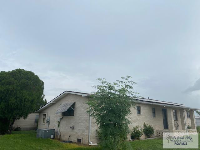 view of side of home featuring cooling unit and a lawn