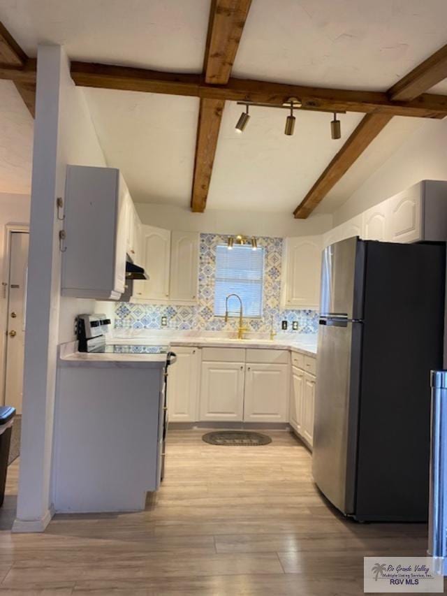 kitchen featuring appliances with stainless steel finishes, light wood-type flooring, tasteful backsplash, sink, and white cabinetry