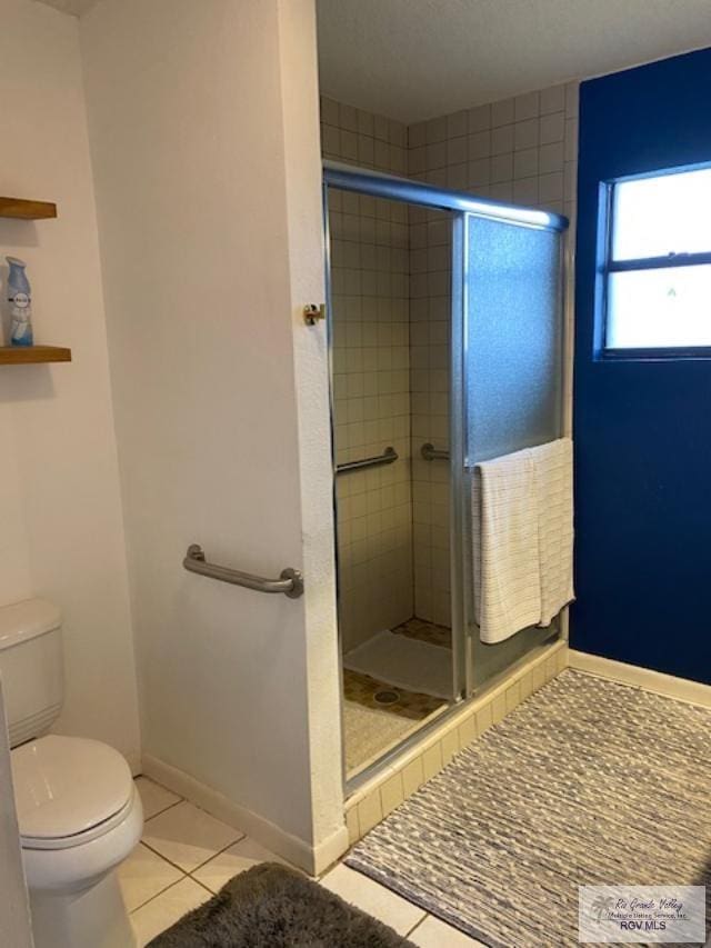 bathroom with tile patterned floors, a shower with shower door, and toilet