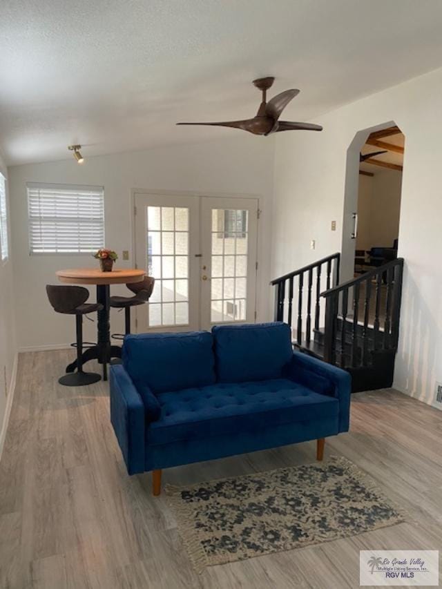 living room with ceiling fan, light wood-type flooring, french doors, and vaulted ceiling