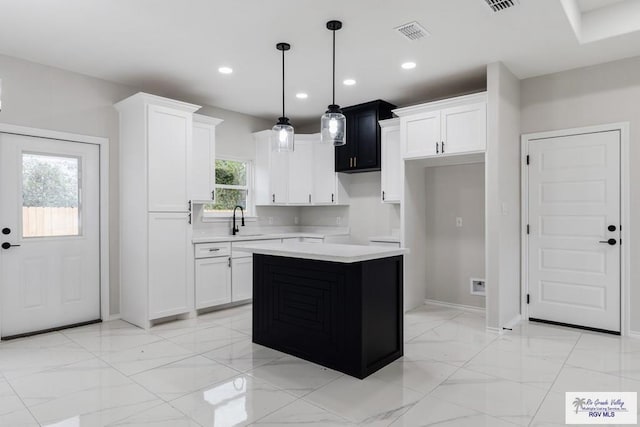 kitchen featuring pendant lighting, sink, white cabinets, and a kitchen island