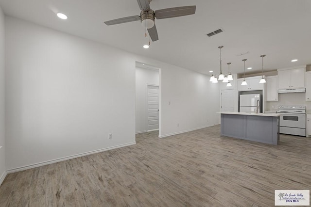 kitchen featuring white appliances, white cabinetry, hanging light fixtures, a center island, and light hardwood / wood-style floors