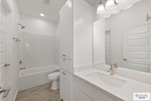 full bathroom with hardwood / wood-style flooring, shower / bath combination, vanity, and toilet