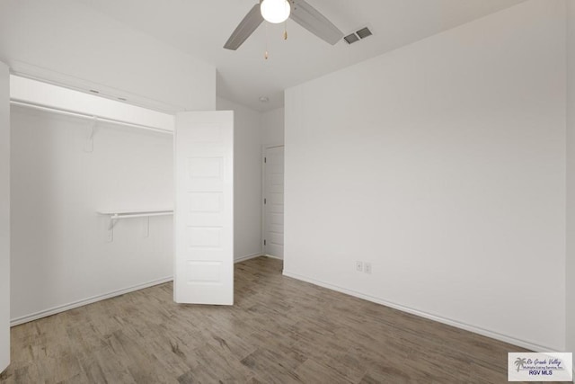 unfurnished bedroom featuring lofted ceiling, hardwood / wood-style floors, a closet, and ceiling fan