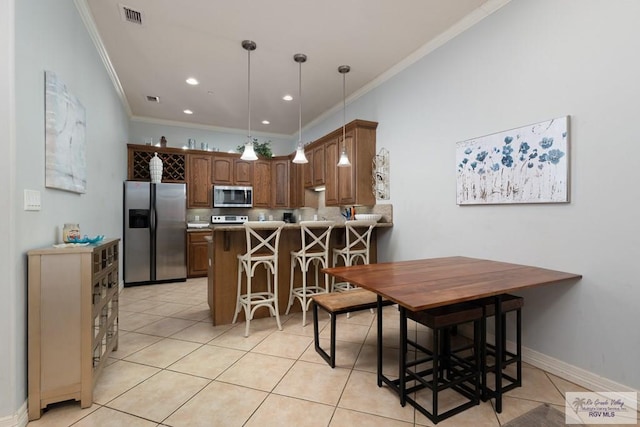 kitchen featuring appliances with stainless steel finishes, hanging light fixtures, a kitchen bar, light tile patterned flooring, and kitchen peninsula