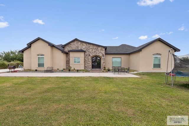 view of front of property featuring a front yard, a trampoline, and a patio area