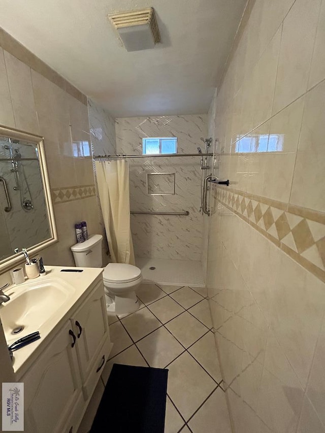 bathroom with vanity, tile patterned floors, a shower with shower curtain, toilet, and tile walls