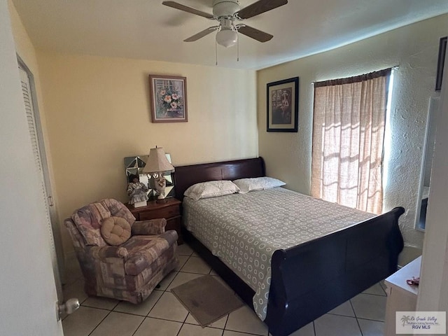 bedroom with ceiling fan, light tile patterned floors, and a closet