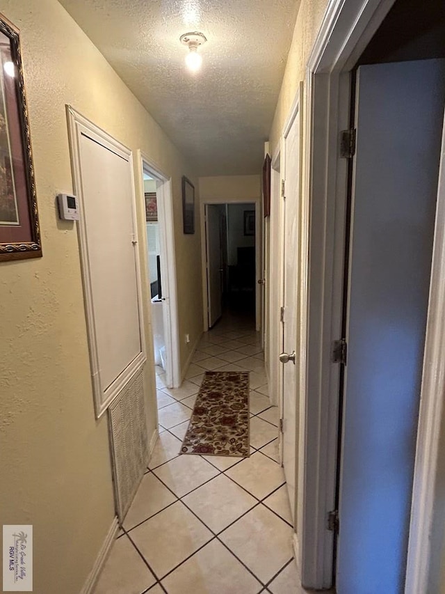 corridor with light tile patterned flooring and a textured ceiling