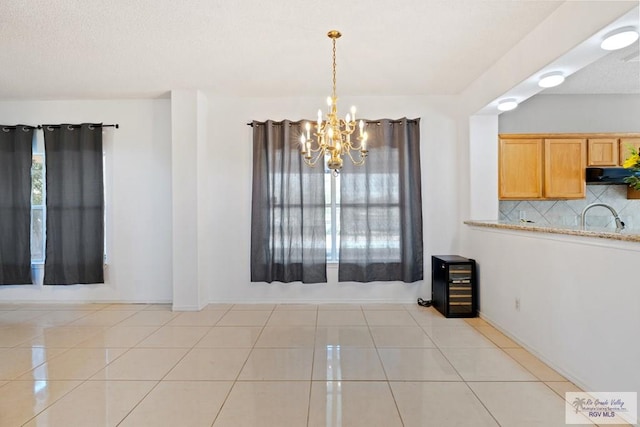 unfurnished dining area with light tile patterned flooring, sink, and a chandelier