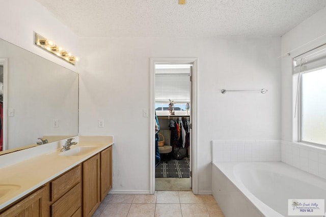 bathroom featuring tile patterned floors, a tub, vanity, and a textured ceiling