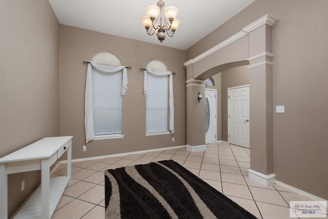 entryway featuring light tile patterned flooring, arched walkways, baseboards, and an inviting chandelier