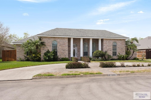 view of front facade with concrete driveway, fence, and brick siding