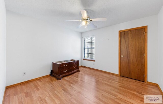 unfurnished bedroom with a ceiling fan, baseboards, light wood finished floors, and a textured ceiling