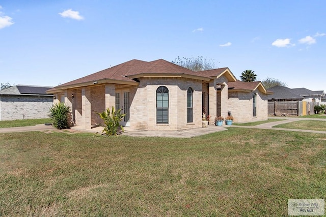 view of front of house featuring brick siding, a front yard, and fence