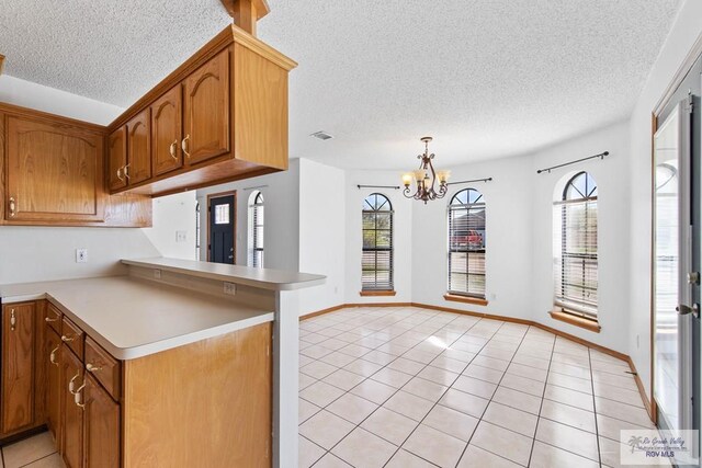 kitchen featuring light tile patterned flooring, a peninsula, a textured ceiling, and light countertops