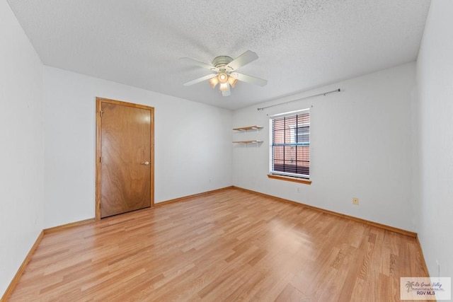 empty room with ceiling fan, baseboards, light wood finished floors, and a textured ceiling