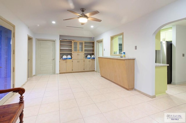 kitchen with stainless steel fridge, light tile patterned floors, ceiling fan, and lofted ceiling