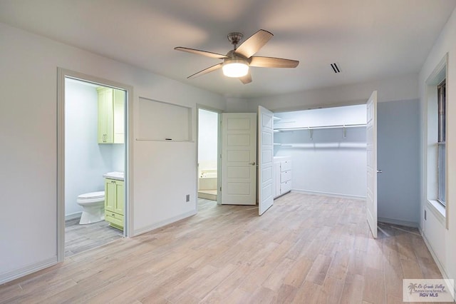 unfurnished bedroom featuring ceiling fan, ensuite bath, light hardwood / wood-style flooring, and a closet