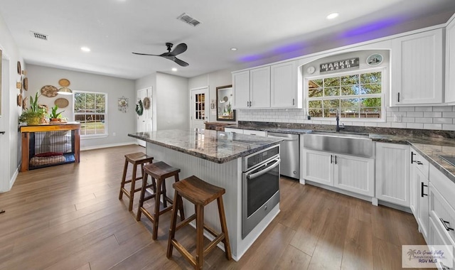 kitchen featuring visible vents, a kitchen island, a kitchen breakfast bar, stainless steel appliances, and a sink