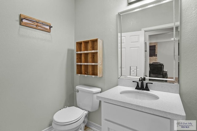 bathroom with toilet, vanity, and baseboards