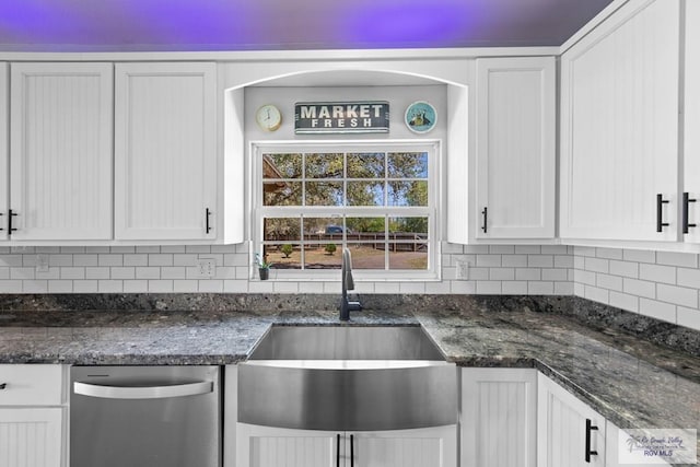 kitchen with a sink, dark stone counters, tasteful backsplash, and white cabinetry