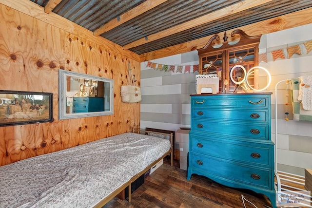 bedroom with dark wood finished floors and wooden walls