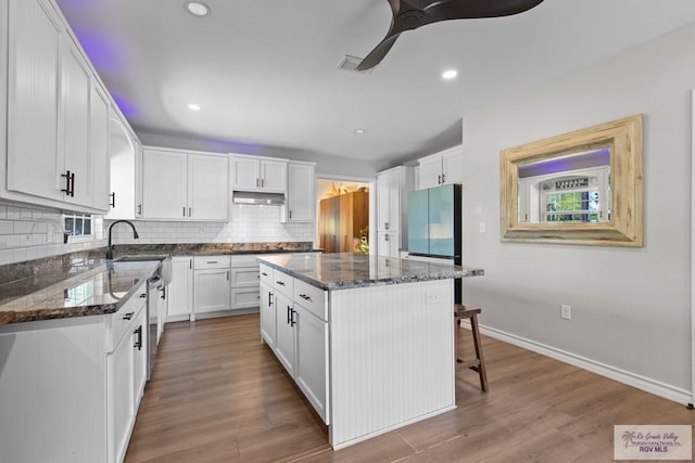 kitchen with tasteful backsplash, visible vents, under cabinet range hood, dark stone counters, and appliances with stainless steel finishes