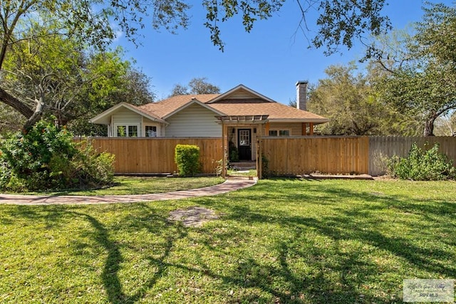 view of front facade with a front lawn, a fenced front yard, and a chimney