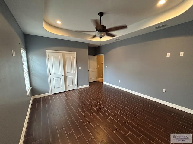 unfurnished bedroom with a closet, ceiling fan, and a tray ceiling