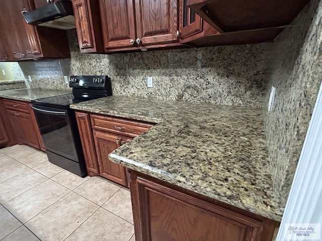 kitchen featuring light tile patterned flooring, light stone countertops, electric range, and decorative backsplash