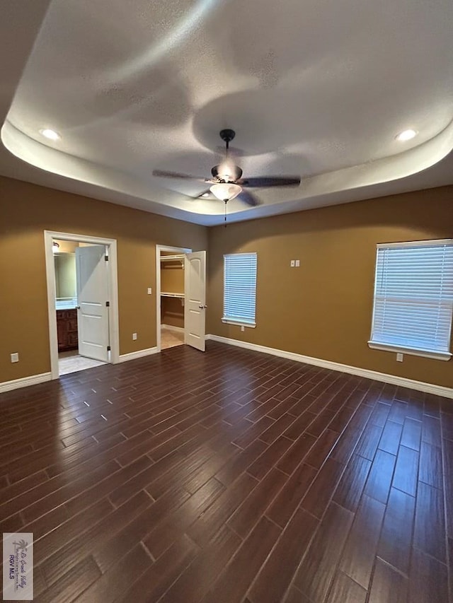 interior space featuring ceiling fan, a tray ceiling, and dark hardwood / wood-style flooring