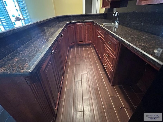 kitchen with dark hardwood / wood-style flooring, sink, and dark stone countertops