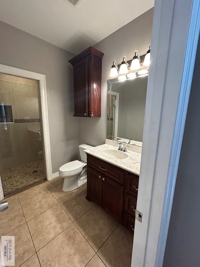 bathroom with tile patterned flooring, vanity, a shower with door, and toilet