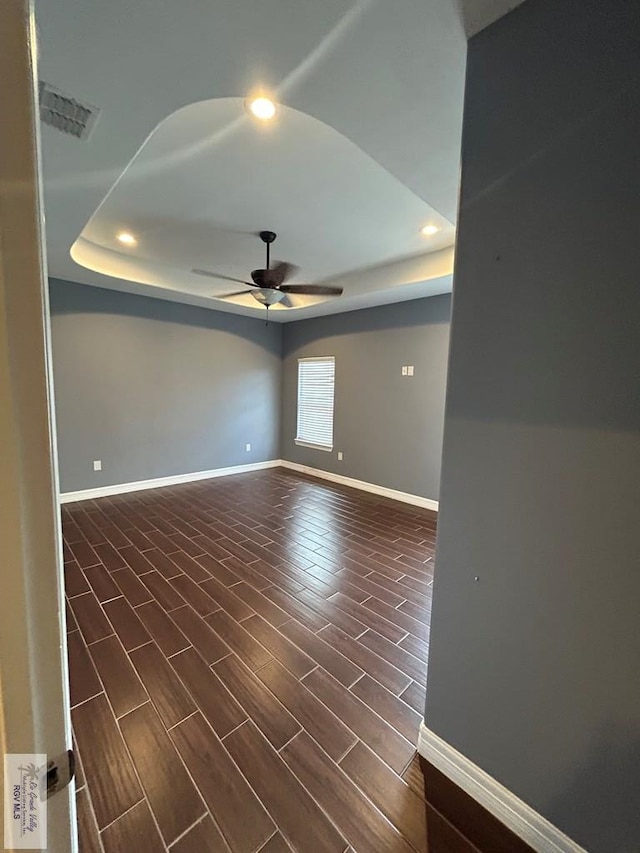 empty room featuring a raised ceiling and ceiling fan