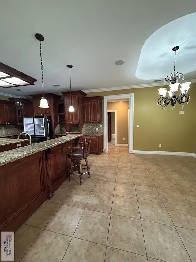 kitchen with light tile patterned floors, ornamental molding, pendant lighting, light stone countertops, and decorative backsplash