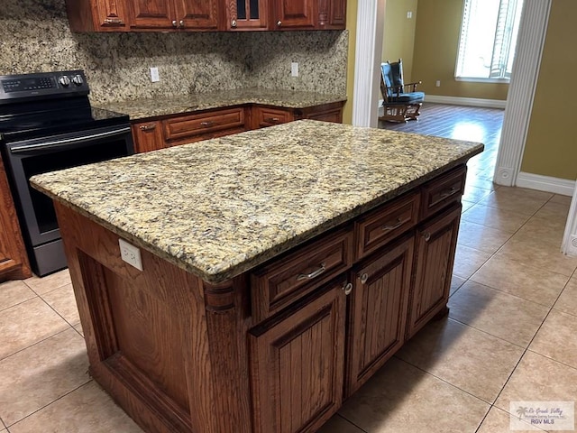 kitchen with a center island, stainless steel electric range oven, light stone countertops, and backsplash