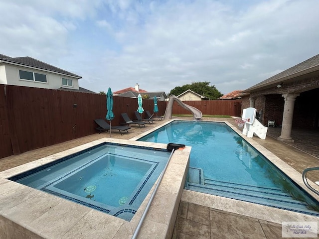 view of pool with an in ground hot tub and a water slide