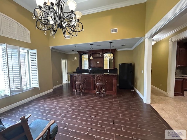 bar featuring hanging light fixtures, dark brown cabinets, ornamental molding, and black fridge