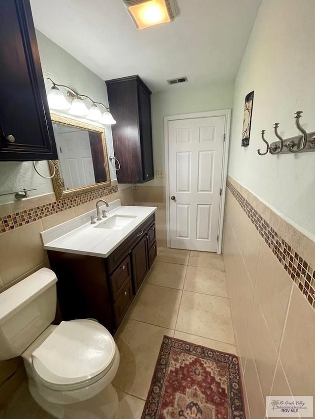 bathroom featuring tile patterned flooring, vanity, tile walls, and toilet