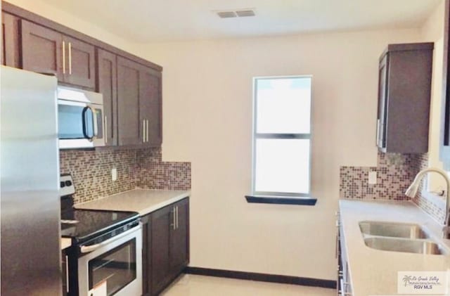 kitchen featuring decorative backsplash, appliances with stainless steel finishes, dark brown cabinets, and sink