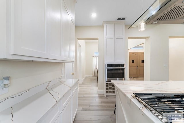 kitchen featuring light stone counters, stainless steel appliances, light hardwood / wood-style floors, white cabinetry, and hanging light fixtures