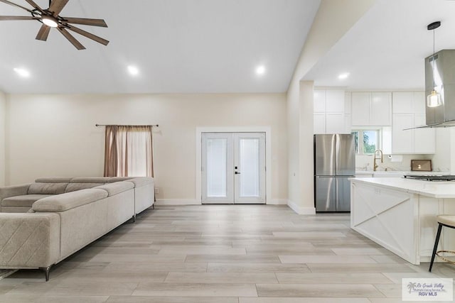 living room featuring lofted ceiling, french doors, sink, ceiling fan, and light hardwood / wood-style floors