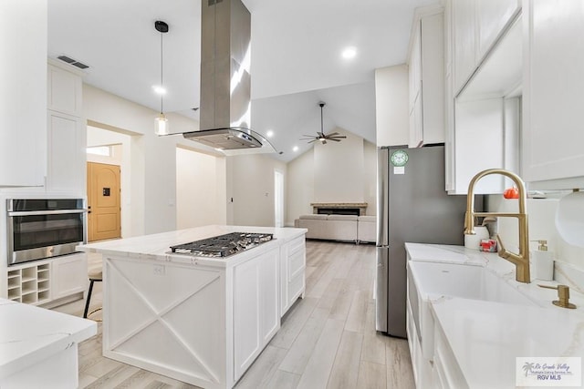 kitchen featuring ceiling fan, light stone countertops, appliances with stainless steel finishes, white cabinetry, and island exhaust hood