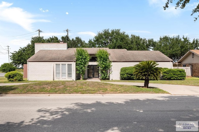 716 E Palm Valley Dr, Harlingen, TX 78550 - view of front facade with brick siding, concrete driveway, and a chimney
