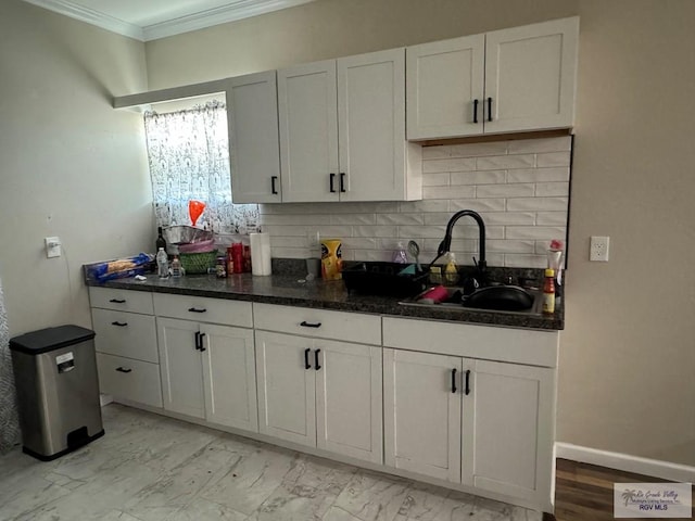 kitchen featuring backsplash, white cabinetry, ornamental molding, and sink