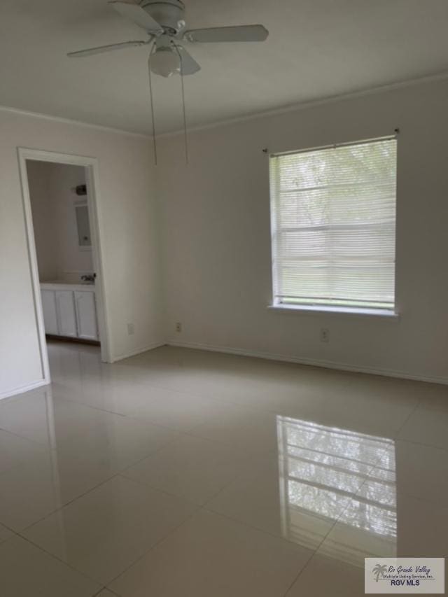 tiled empty room featuring ceiling fan and crown molding